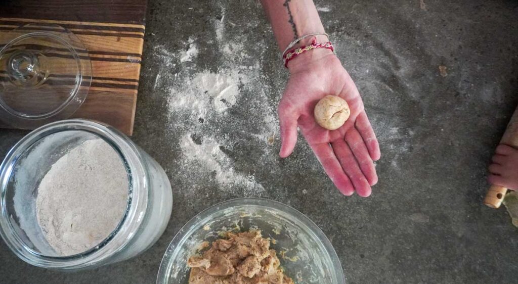 hand holding dough ball of sourdough tortillas over concrete countertop