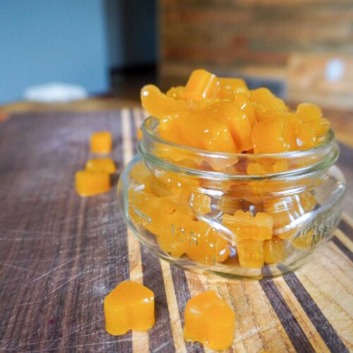 homemade 3 ingredient fruit gummies in a glass jar on a homemade cutting board