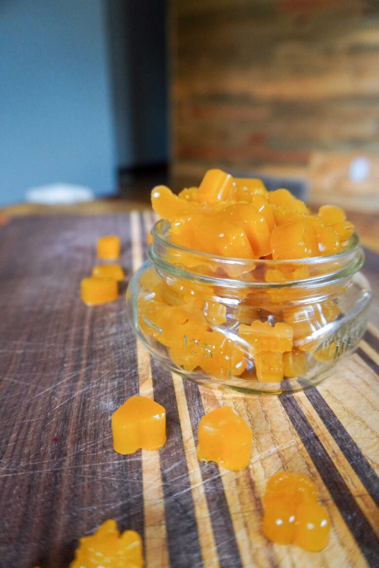 homemade 3 ingredient fruit gummies in a glass jar on a homemade cutting board