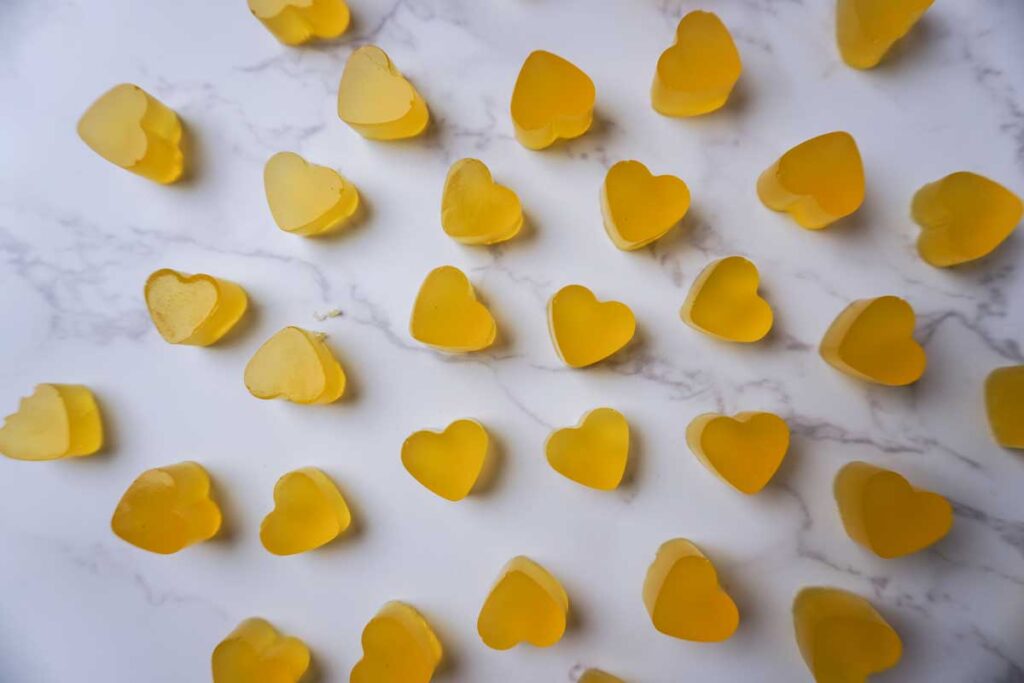 Homemade fruit gummies shaped like hearts spread out on a countertop
