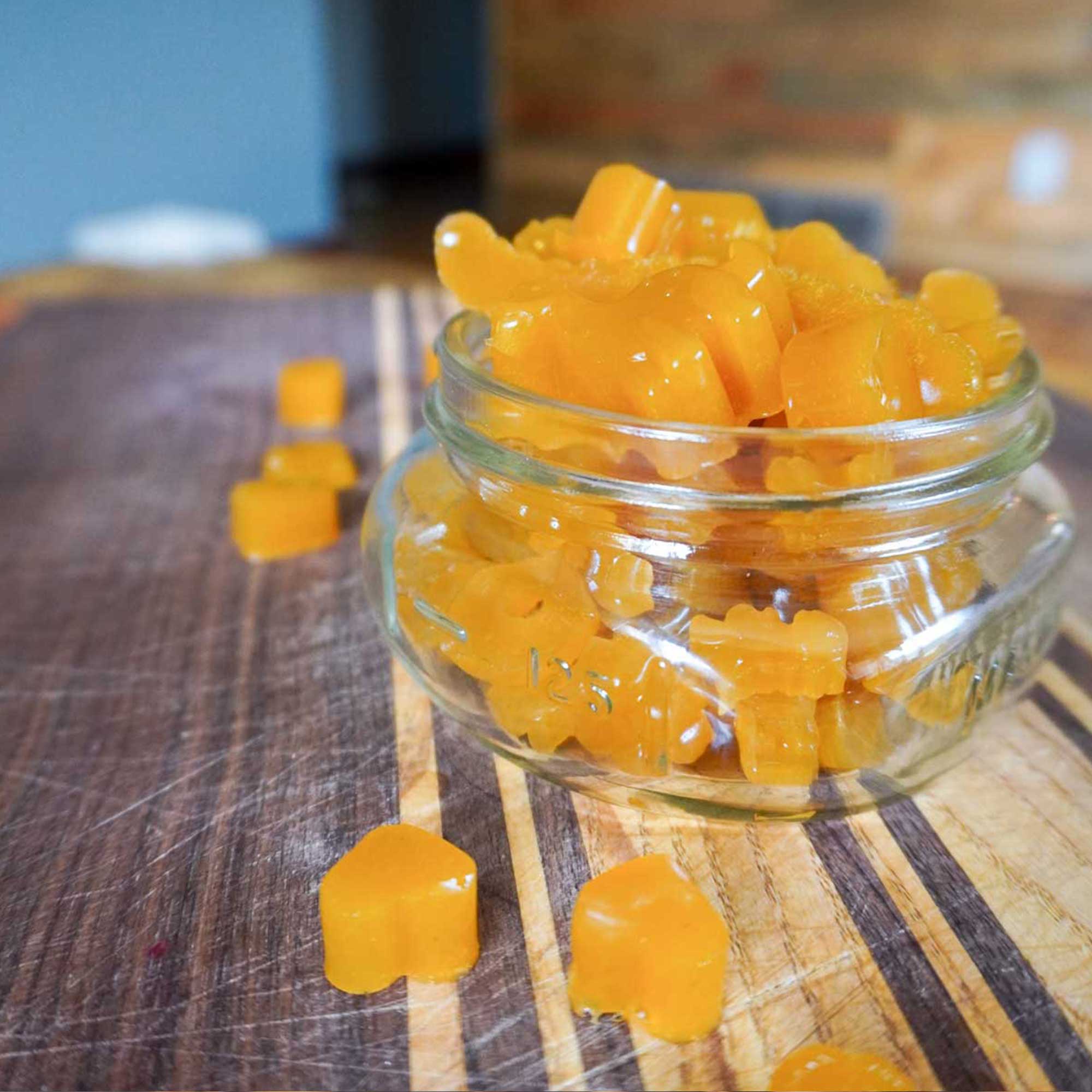 homemade 3 ingredient fruit gummies in a glass jar on a homemade wood cutting board