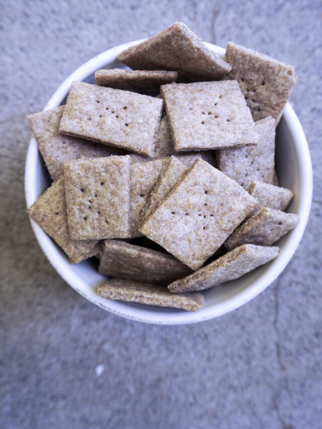 white glass bowl full of whole wheat sourdough butter crackers on a concrete countertop