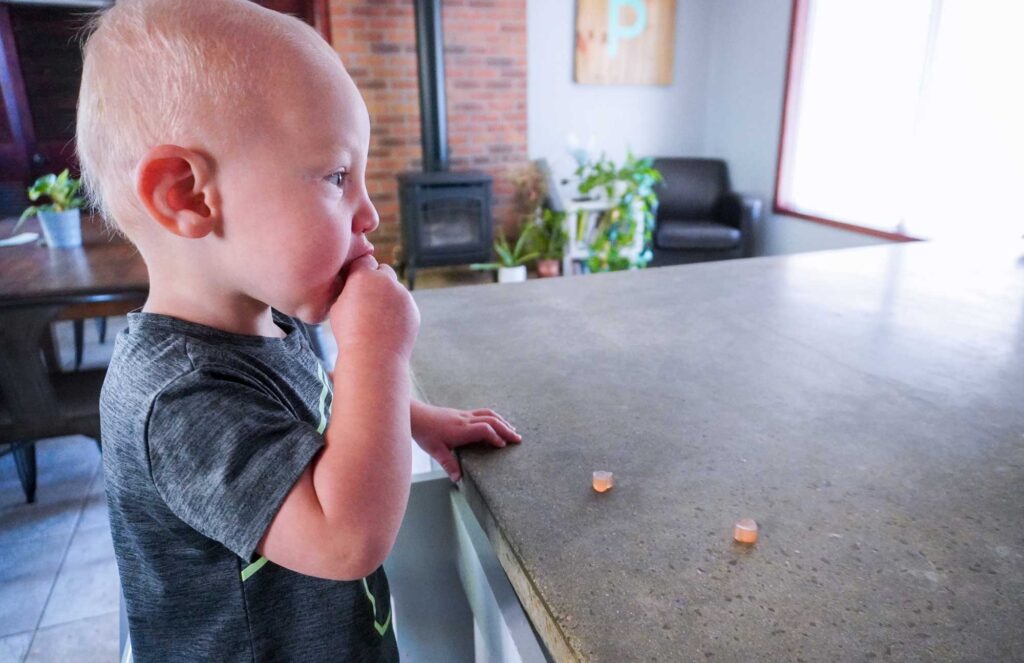 toddler standing and eating homemade fruit gummies at a concrete countertop