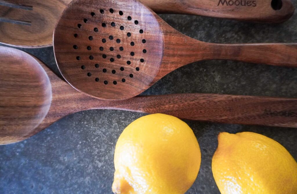 close up top view of three wooden spoons next to two lemons
