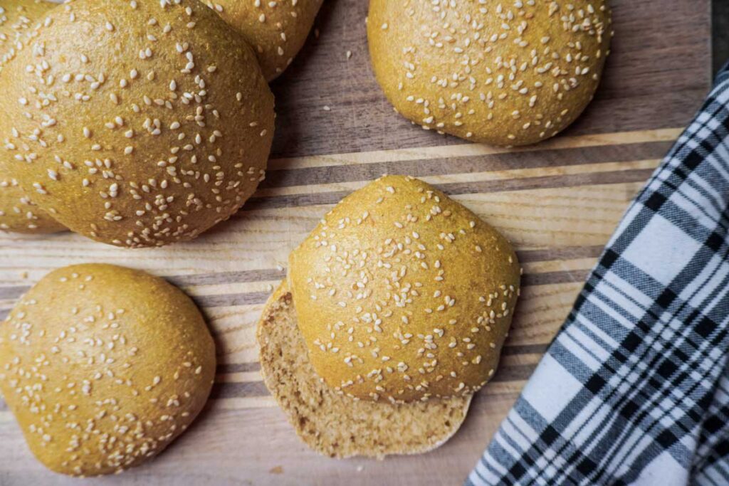 Top view of several hamburger buns made with fresh milled flour on a cutting board