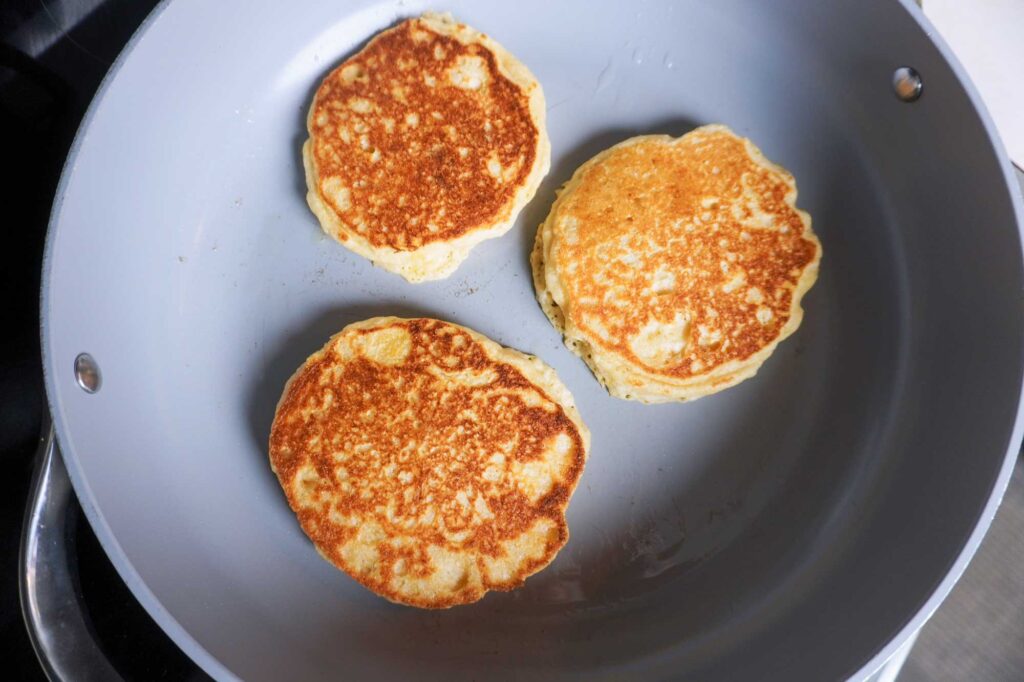 Golden brown fresh milled flour pancakes in a grey frying pan
