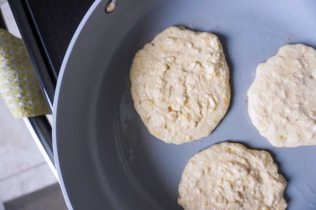 Pancake batter in a large frying pan cooking.