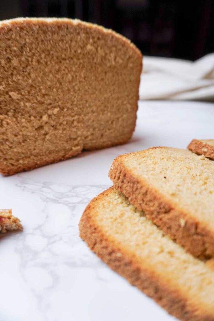 Close up view of sliced fresh milled flour bread with a loaf behind.