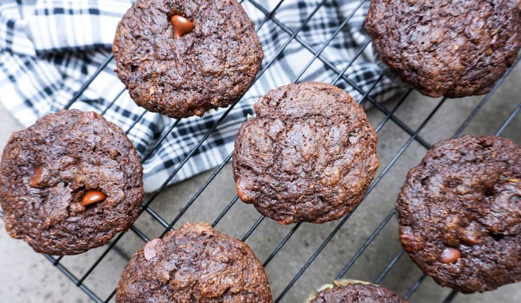 Several dark chocolate muffins cooling on a wire rack.