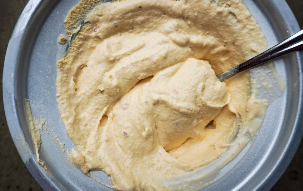 Large bowl with fresh homemade peach ice cream and a spoon.