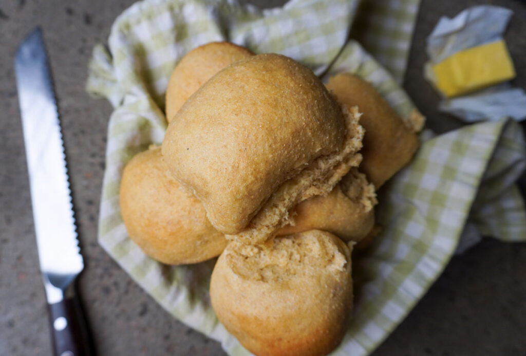 A bowl full of fresh and golden brown whole wheat dinner rolls