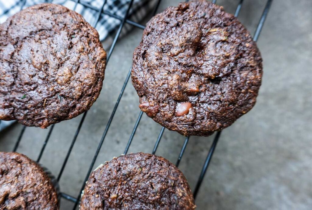 Close up view of four chocolate muffins with chocolate chips on a cooling rack