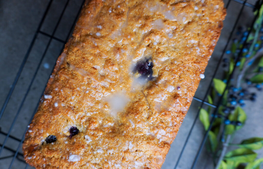healthy lemon blueberry quick bread on a cooling rack with lemon glaze
