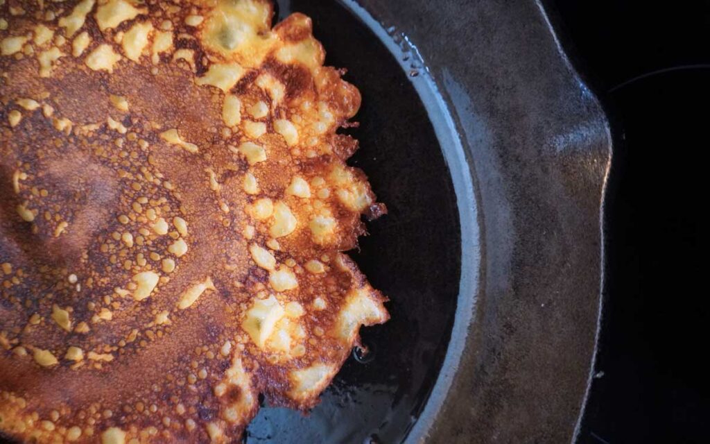 Sourdough crepe in a cast iron pan with crispy edges