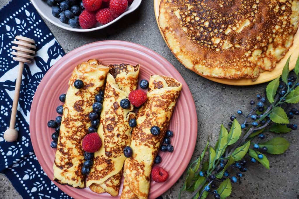 A breakfast spread with rolled up sourdough crepes and fresh fruit