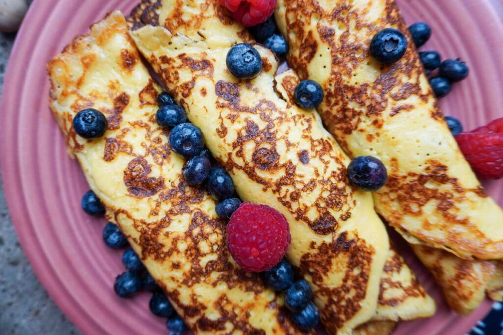 Close up of three rolled up sourdough crepes with fresh fruit