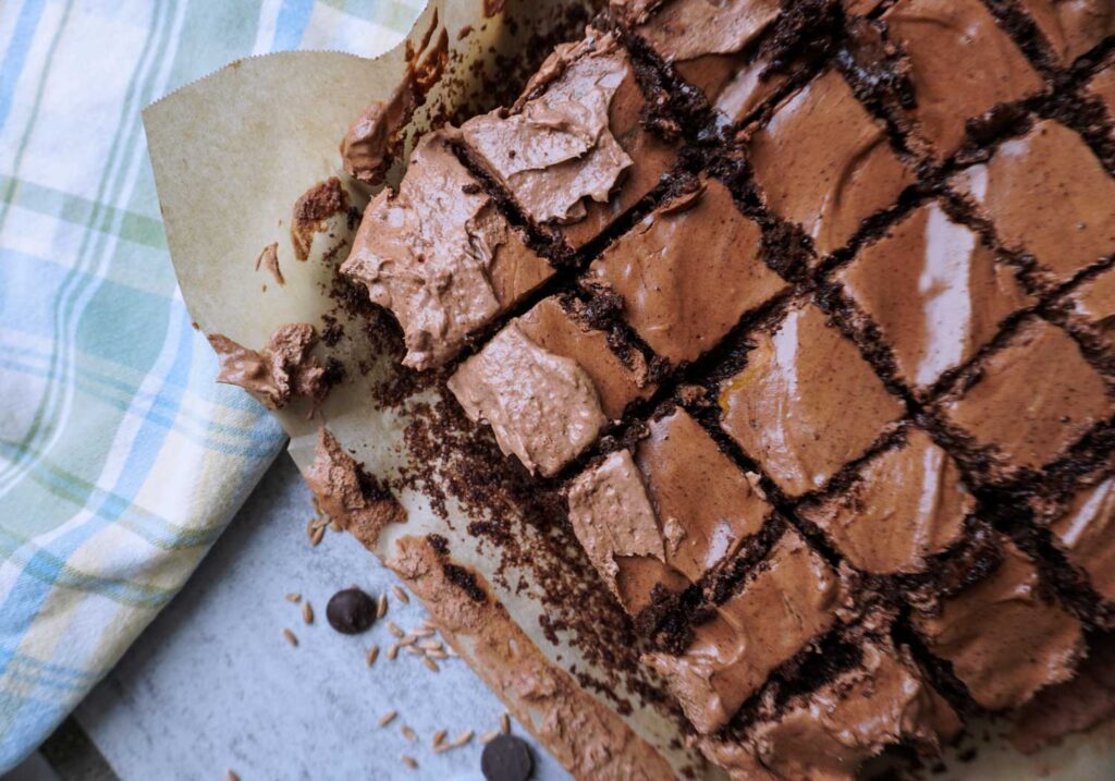 A pan of freshly baked spelt brownies with frosting on top