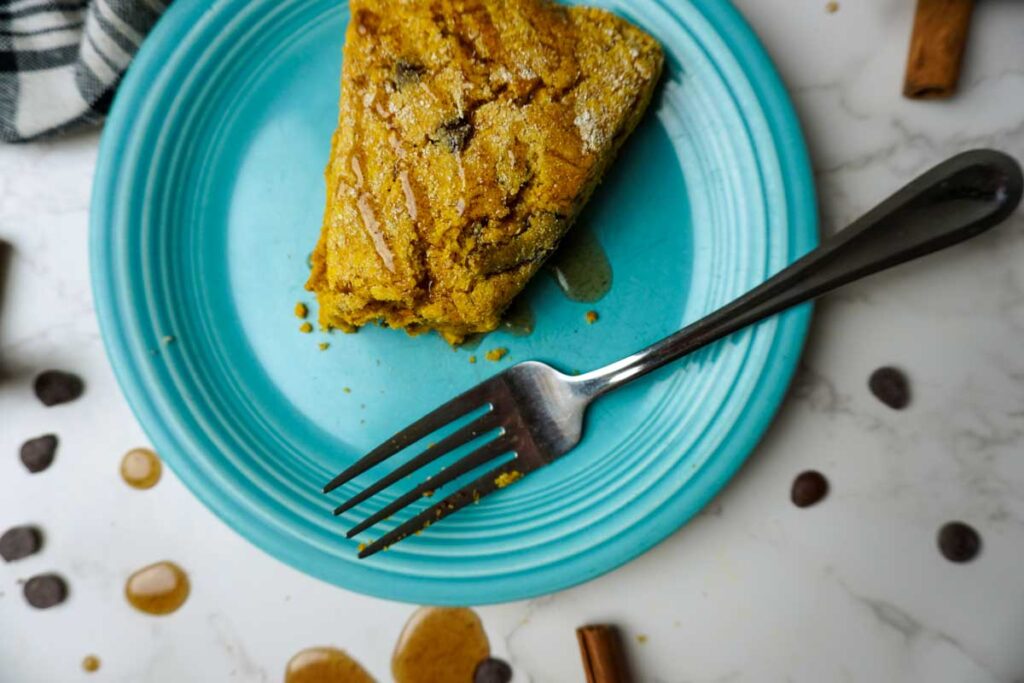 Partially eaten pumpkin scone on a blue plate with a fork