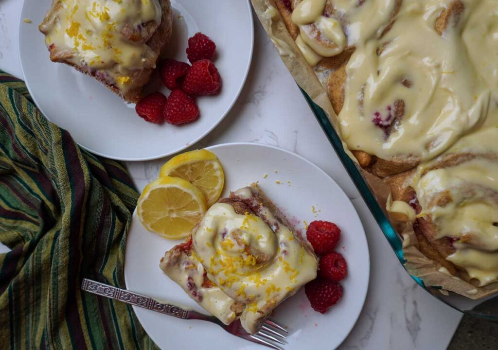 Tray of lemon raspberry rolls next to two rolls on plates