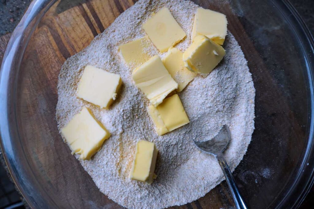 Bowl of flour with chunks of butter on top