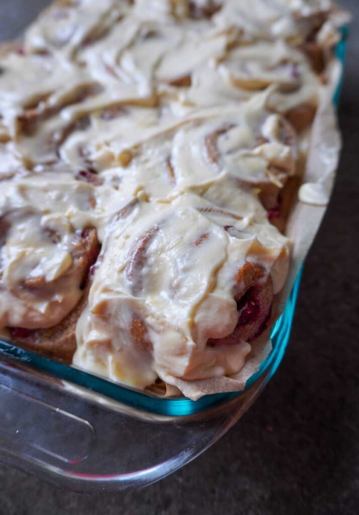 Frosted lemon raspberry rolls in a glass pan.