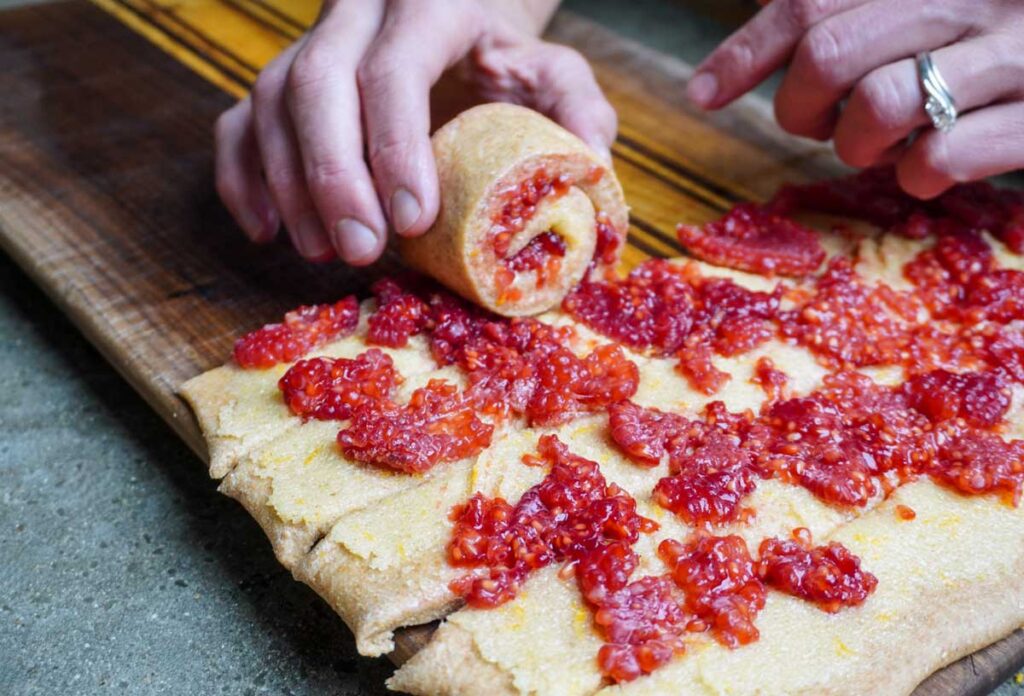 Hand carefully rolling up lemon raspberry rolls.